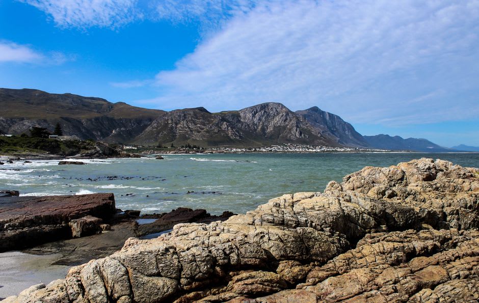 Côte rocheuse et mer avec les montagnes en arrière-plan à Hermanus, Afrique du Sud