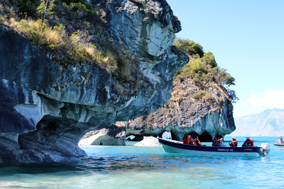 Boat gliding through a narrow marble channel with veined blue-gray stone walls on General Carrera Lake