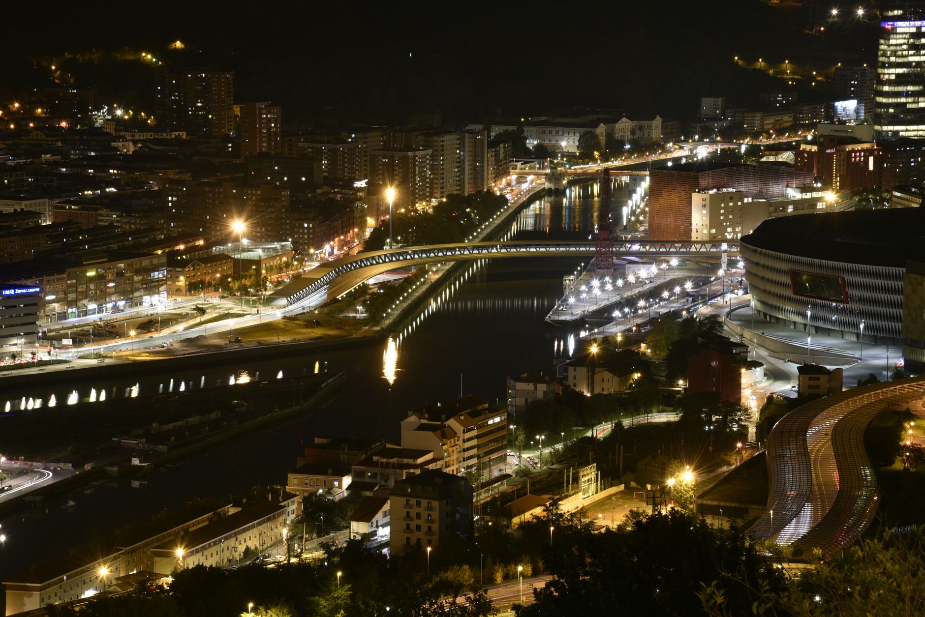 The Nervión river waterfront at dusk with Bilbao's bridges and skyline reflected in the water