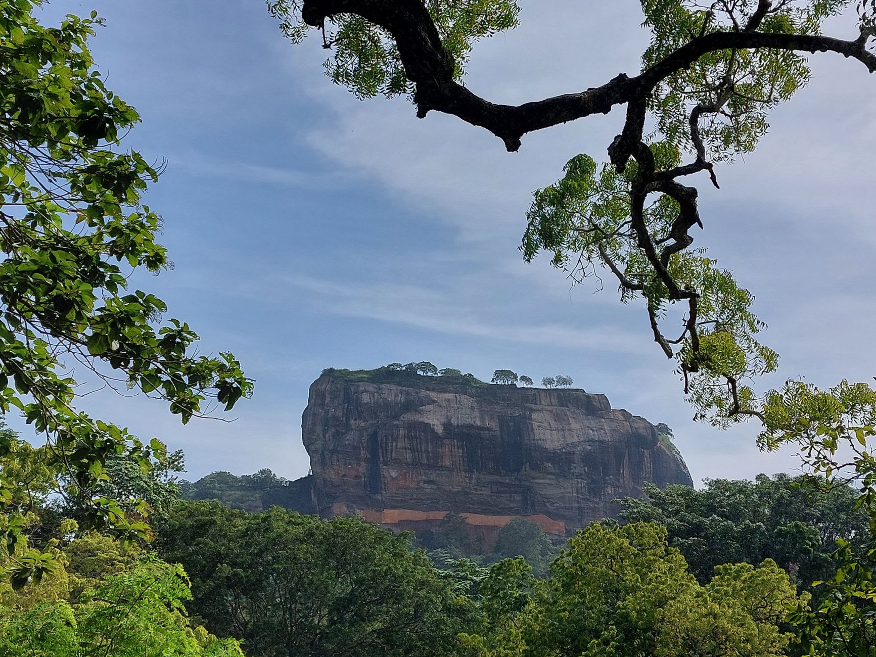 The Sigiriya frescoes: three bare-chested female figures painted in orange and yellow against the rock face, holding flowers, their features still vivid after fifteen centuries