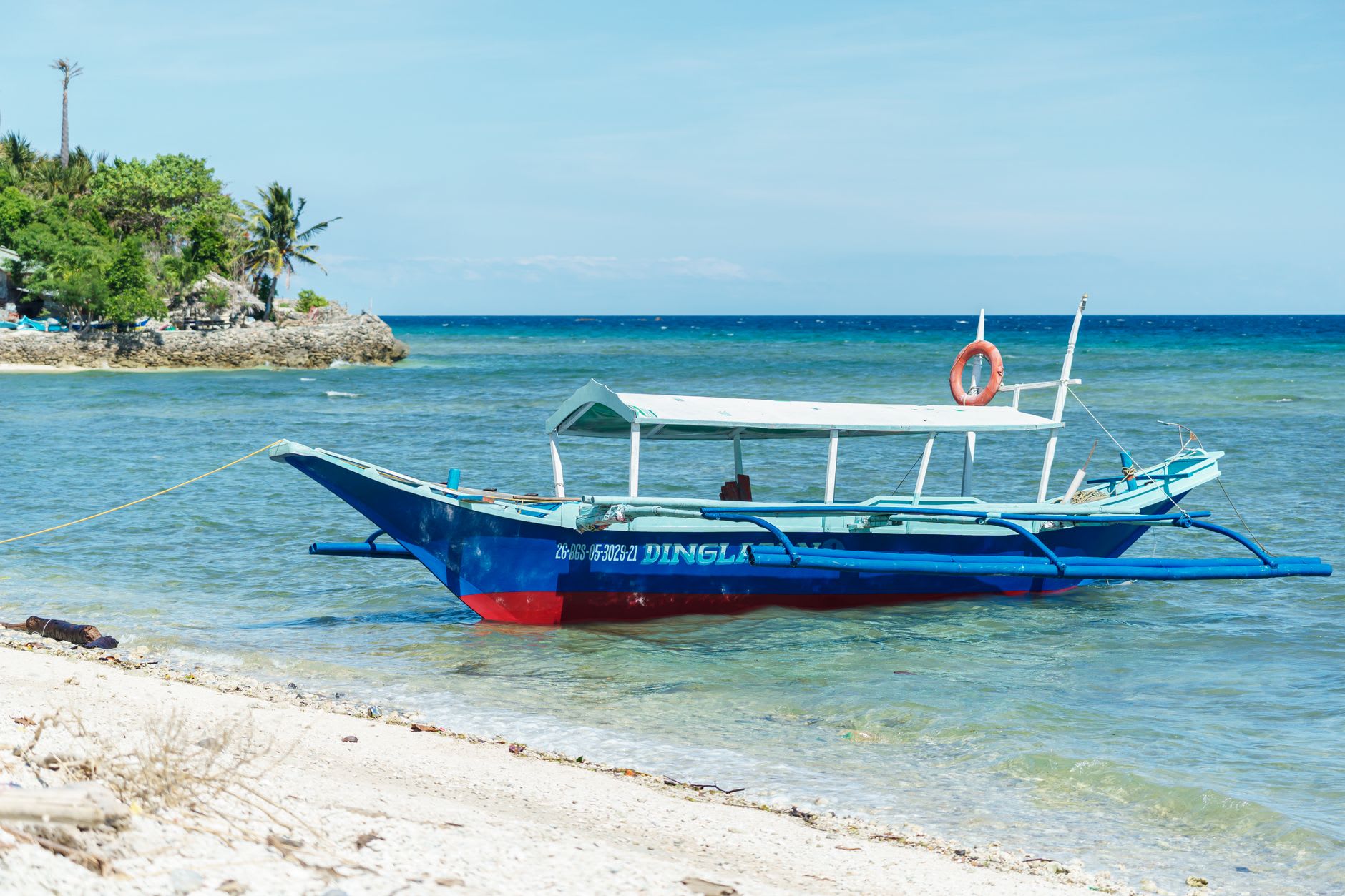 A half-built wooden phinisi schooner rising on props on the beach at Tanah Beru near Tanjung Bira, shipwrights shaping the hull with hand tools