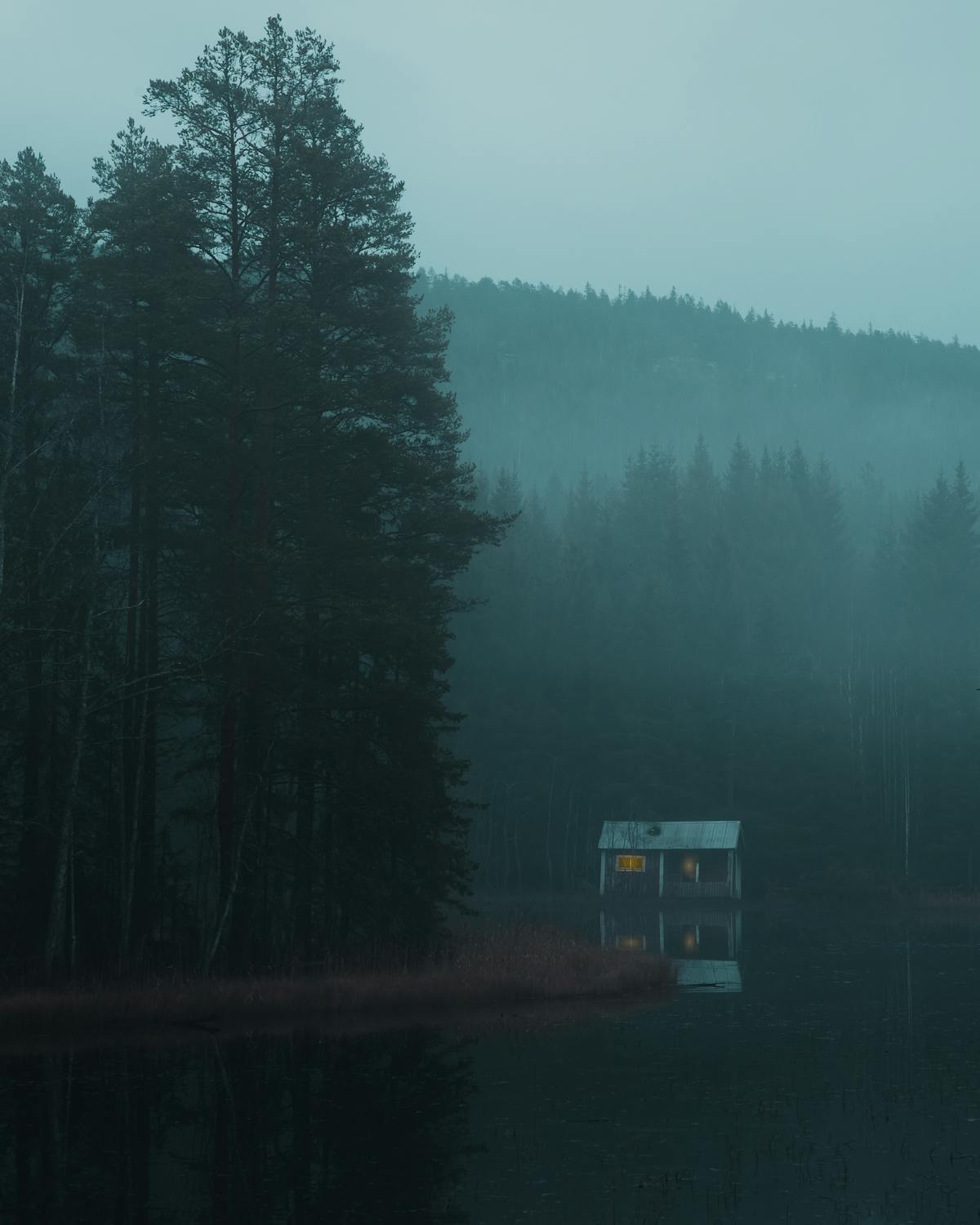 A misty morning cabin beside a tranquil Swedish lake
