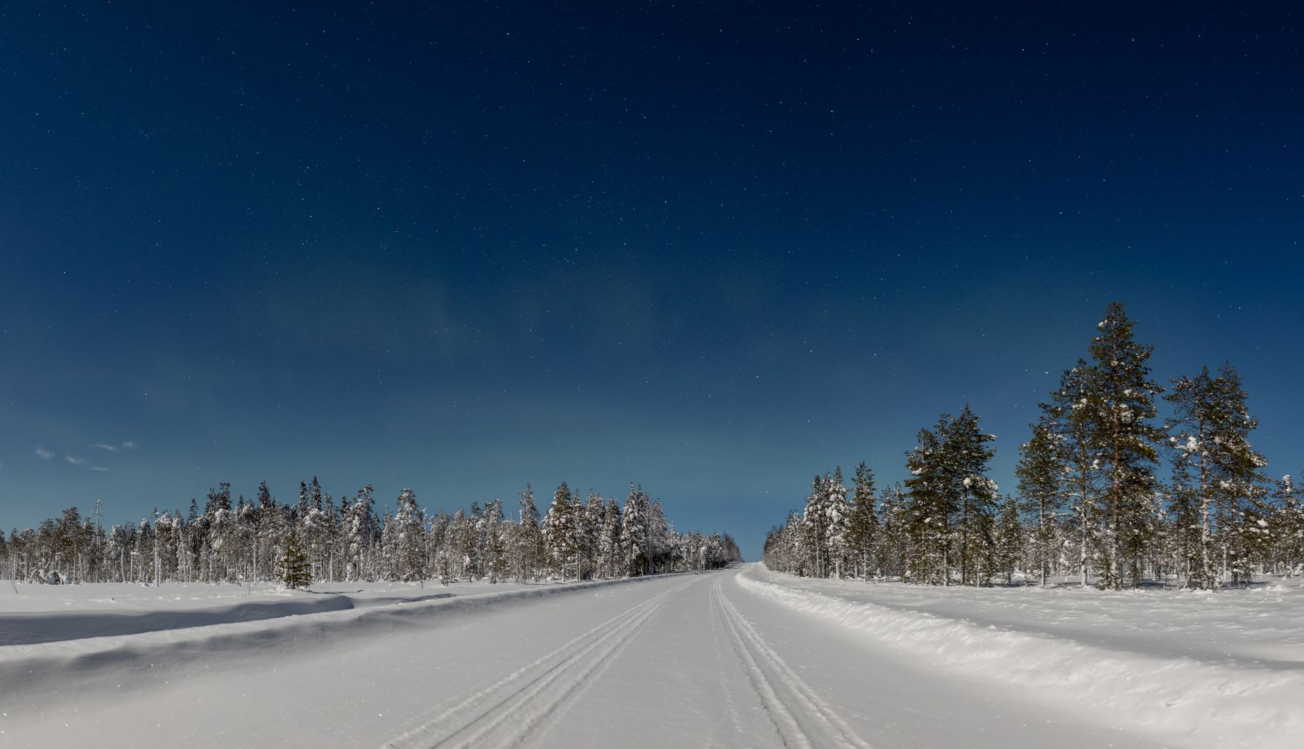 The dark red wooden church of Jukkasjärvi under snow