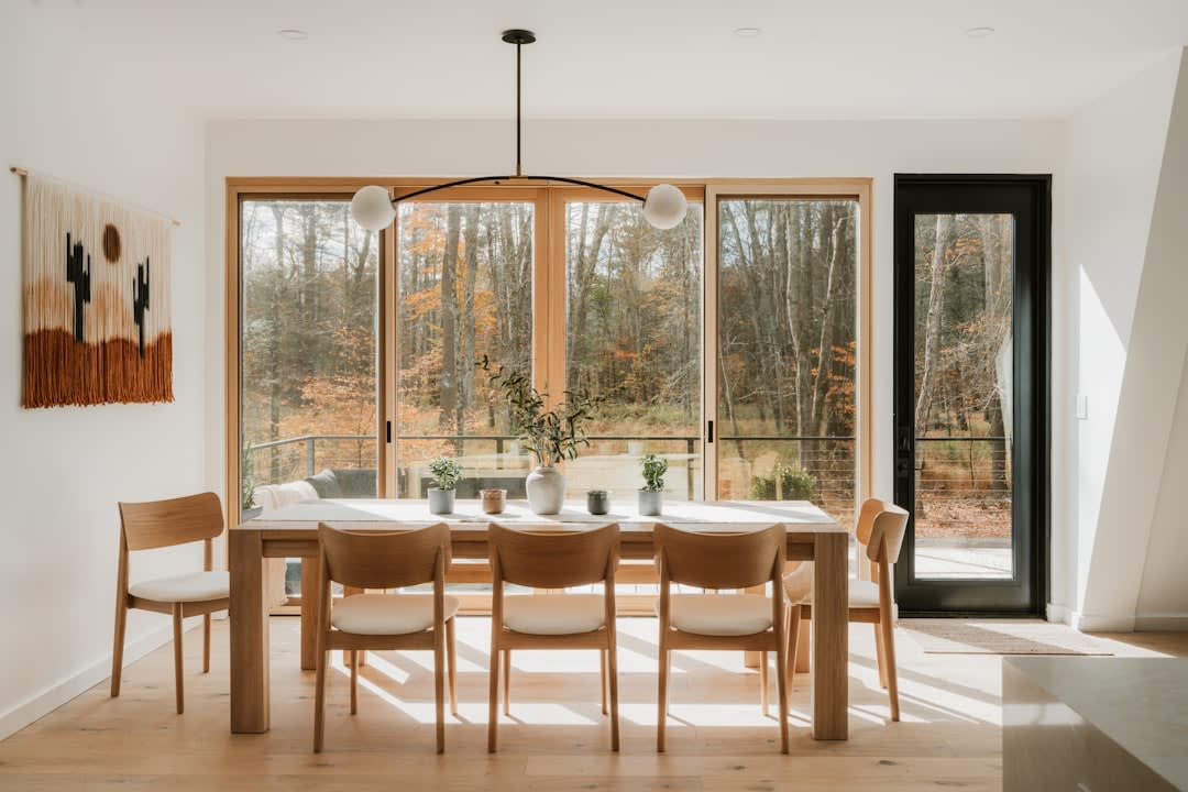 Wild game dinner plated on a wooden table inside a treetop dining room, forest visible through the window