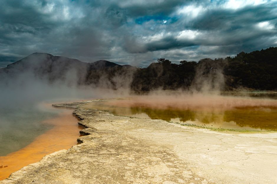 Thermal Valley's milky jade-green sulfuric pool with dense steam rising off the surface, boardwalk visible at the edge