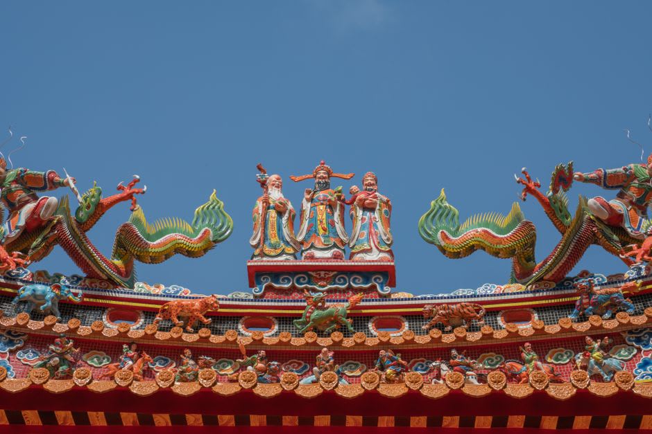 An elaborate sand sculpture on Fulong Beach depicting a dragon coiled around a tower, with the ocean visible behind it