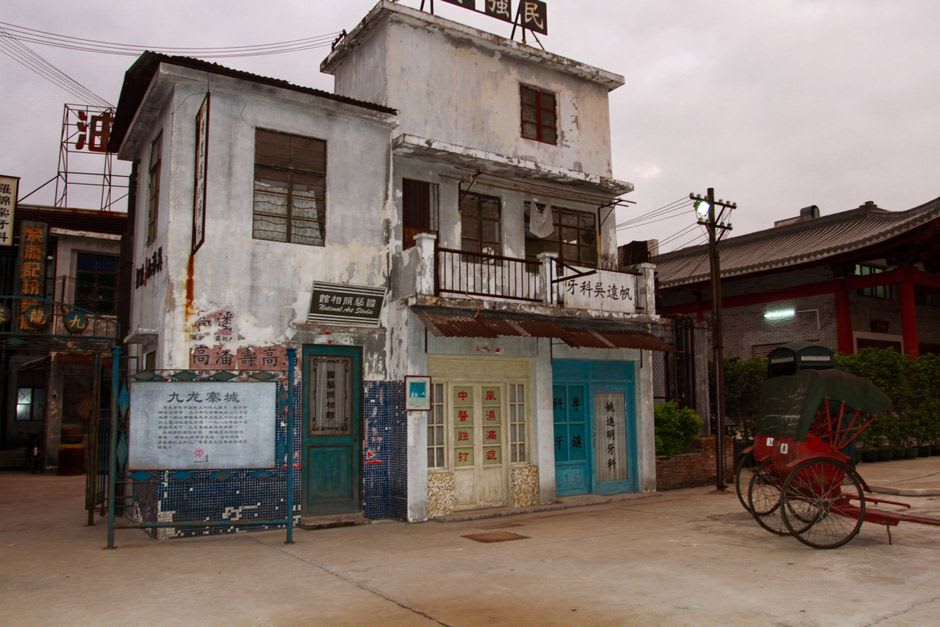 Vendedores locales y scooters pasando bajo una puerta de ciudad de piedra en el casco antiguo de Hengchun, en el sur de Taiwán