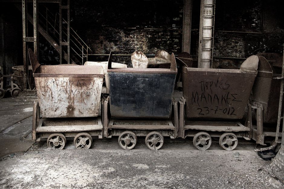 Rusted mining rail carts and equipment preserved on the hillside above Houtong village