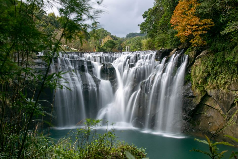 Shifen Waterfall's wide curtain of falling water crashing into a turquoise pool below, mist rising from the impact
