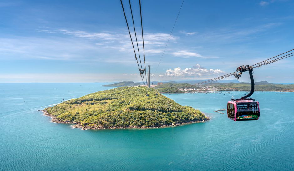 Un teleférico ascendiendo por una colina verde sobre la costa del Pacífico en Farglory Ocean Park
