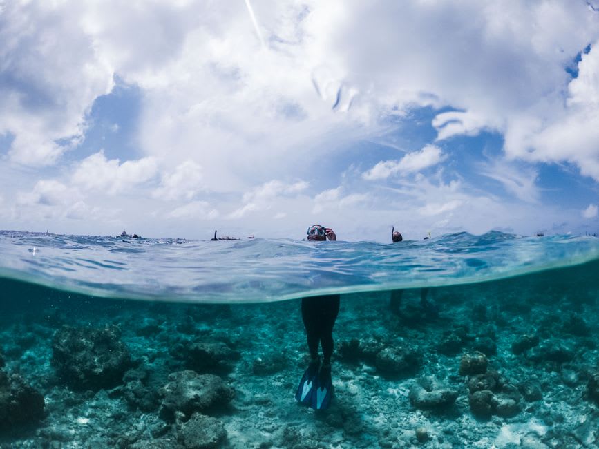 A snorkeler floating above clear turquoise water and coral near Shihlang on Green Island