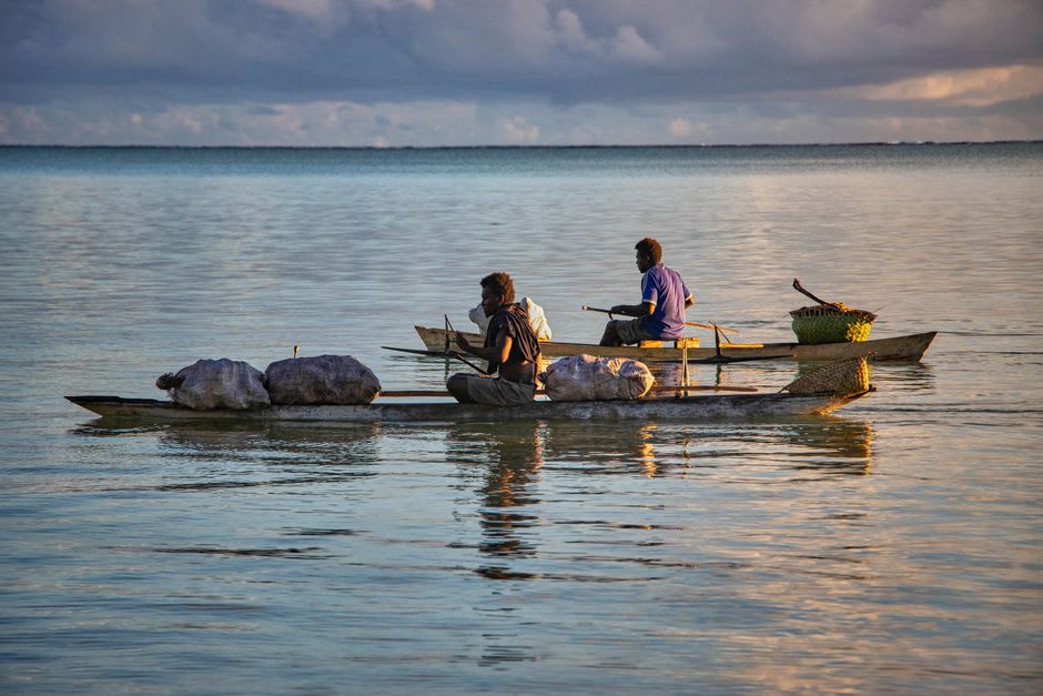 Dos hombres Tao tallando a mano un tatala tradicional de madera en la Isla Orquídea