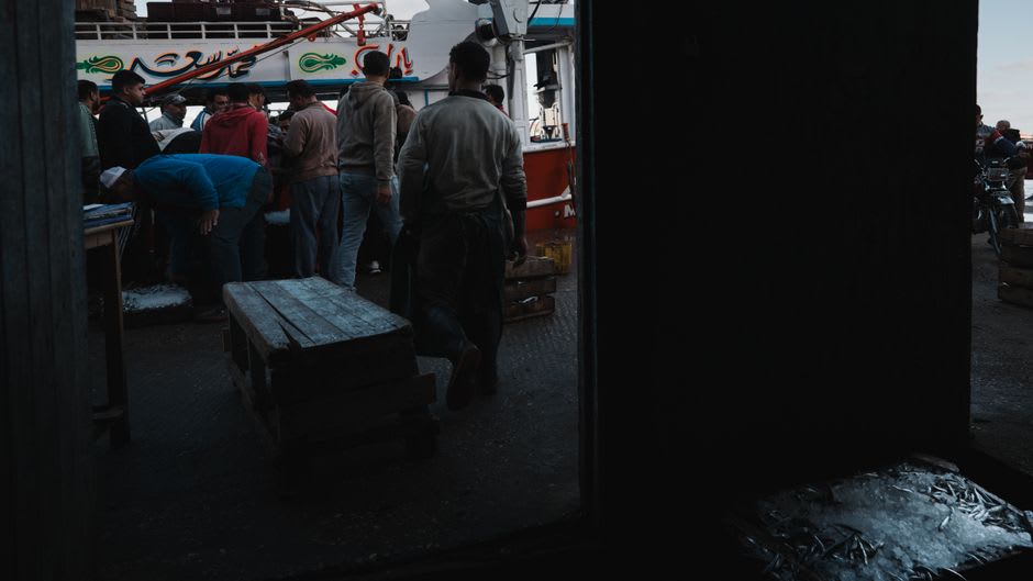 Arrastreros pesqueros descargando cajas de pesca fresca en el Puerto de Wuqi al amanecer