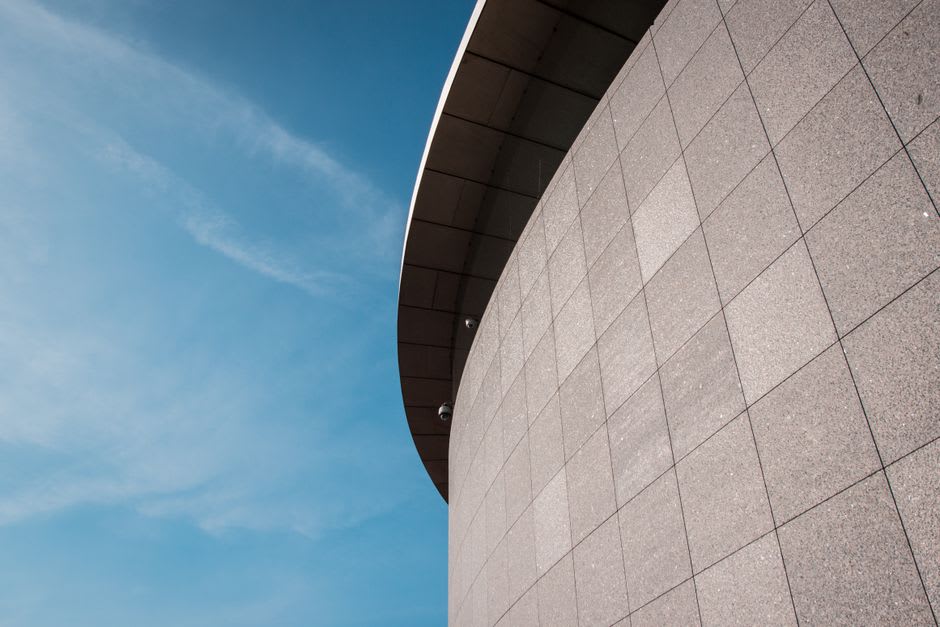 The curved concrete and glass exterior of the Yingge Ceramics Museum reflecting the sky