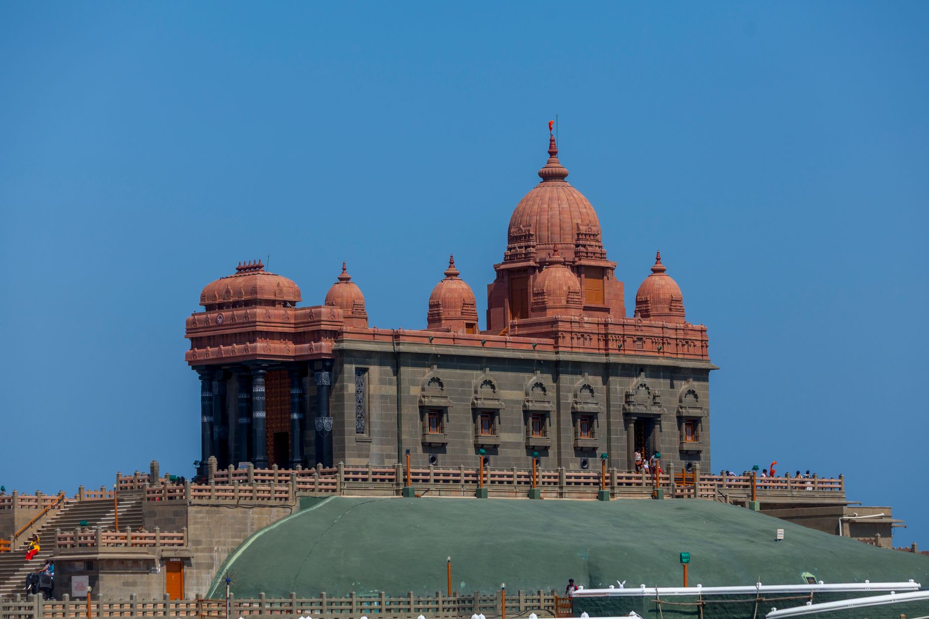 The towering stone statue of the Tamil poet Thiruvalluvar viewed from the ferry deck against a bright morning sky