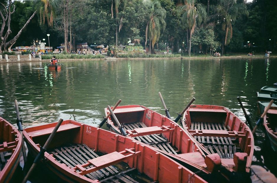Rowboats on the calm emerald water of Yercaud Lake with forested hills behind