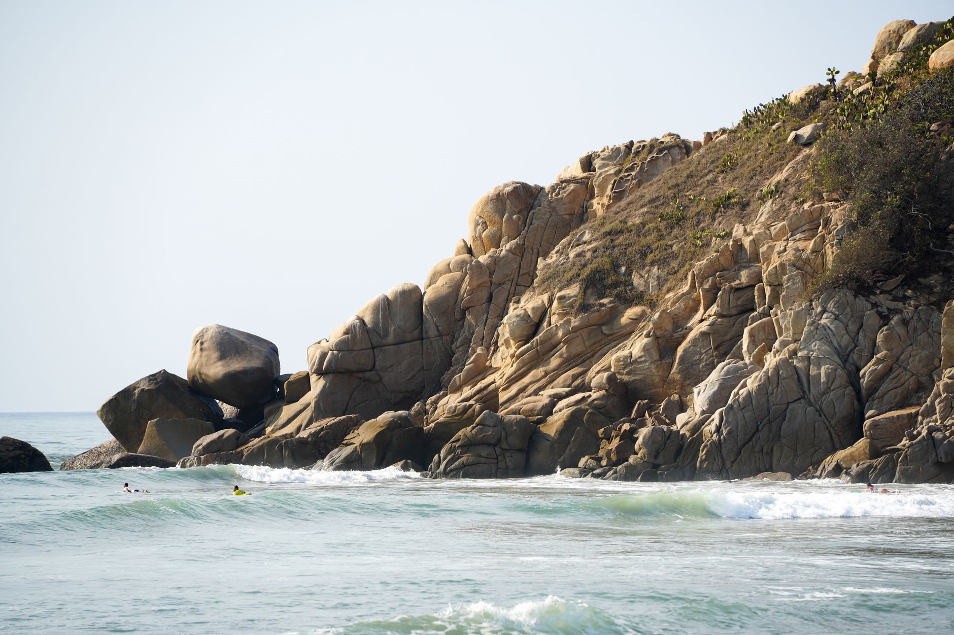 A large iguana sunning itself on a warm granite boulder at Canaveral beach in Tayrona park with the sea behind