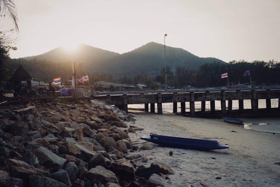 Turquoise water lapping against a quiet beach with longtail boats at anchor