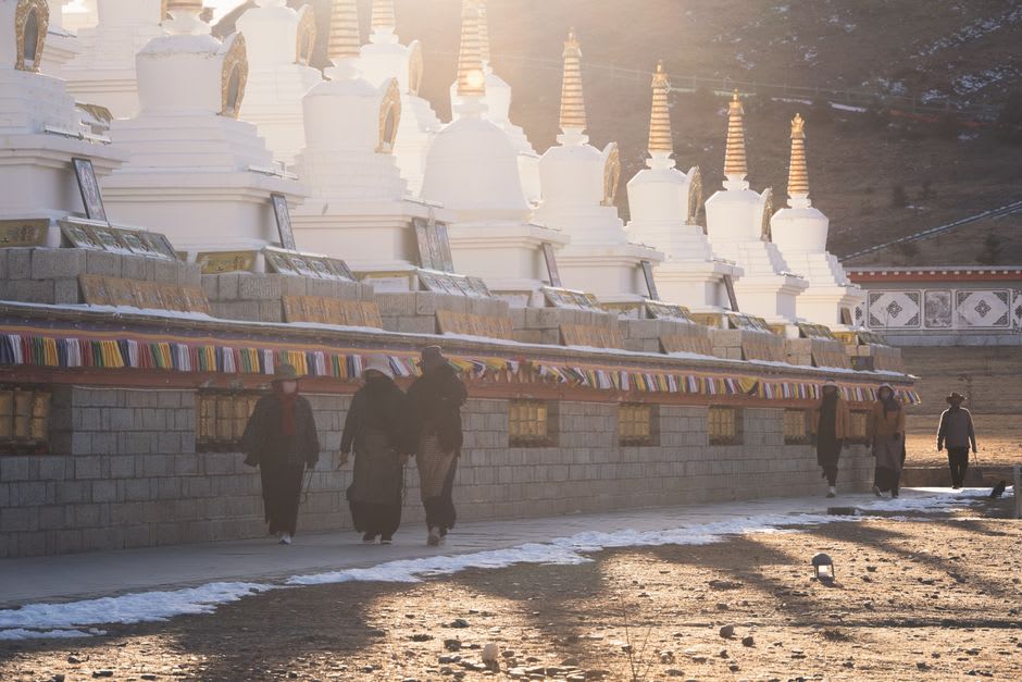 Pilgrims circling the ridge path above Ganden Monastery with prayer flags strung across the rocks