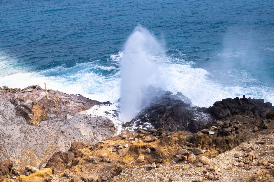 Sea spray bursting through a volcanic blowhole on the exposed rock shelf at Mapu'a 'a Vaea