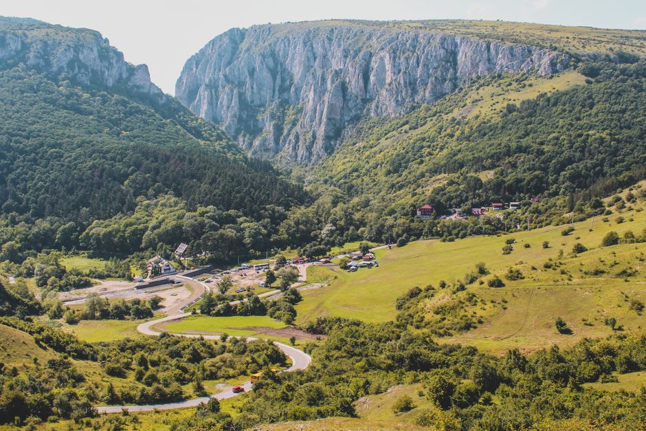 Hikers walking the flat riverside trail beneath the sheer limestone walls of Turda Gorge