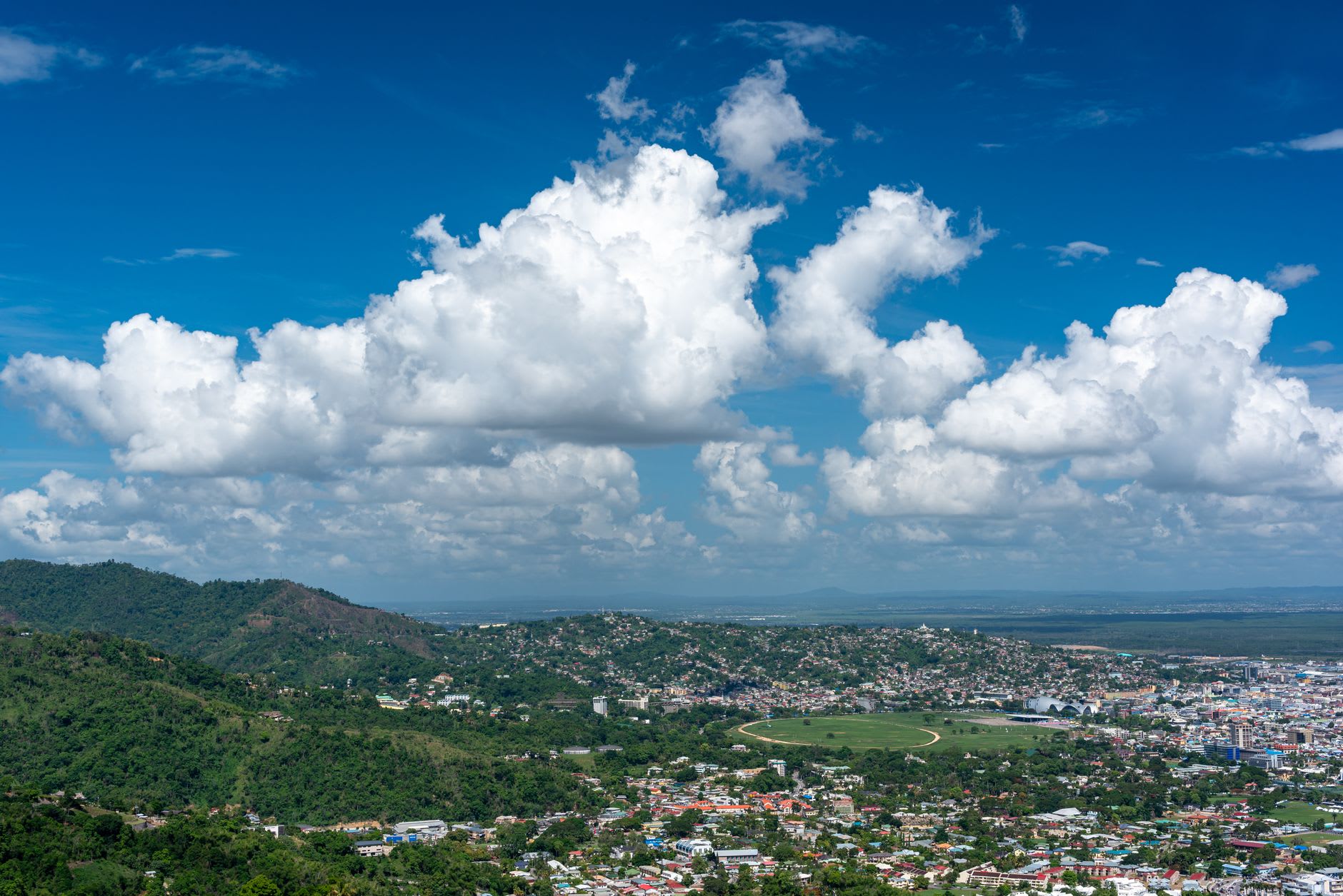 The stone ramparts and old cannons of Fort King George above Scarborough, with palm trees and the blue Caribbean coastline far below.