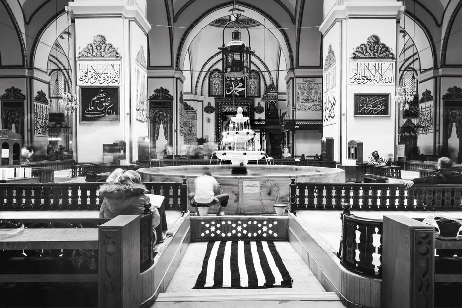 The interior of Ulu Camii in Bursa, showing the central indoor ablution fountain beneath an open oculus
