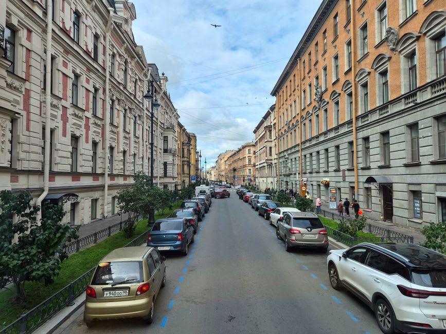 A row of 19th-century Russian imperial stone buildings along a wide Kars avenue, with storks nesting on the chimneys