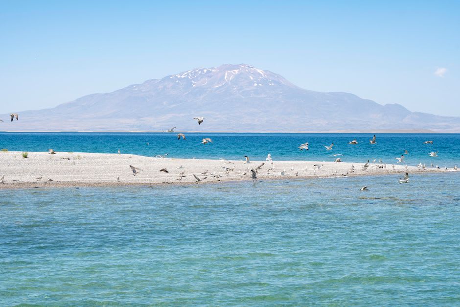 Mount Nemrut's volcanic caldera rising above the turquoise waters of Lake Van