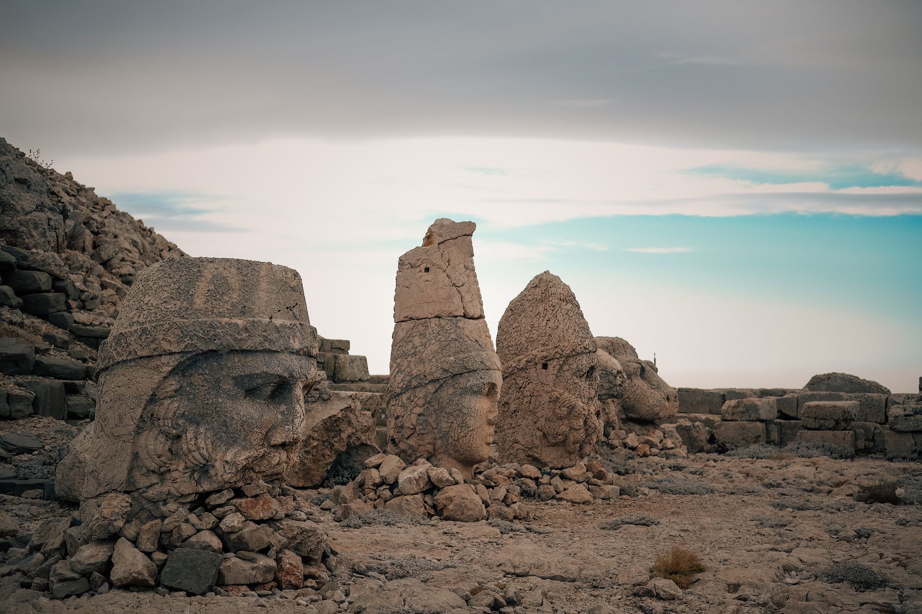 The heads on the West Terrace in softer morning light, with a carved stone relief of Antiochus and the gods visible in the background