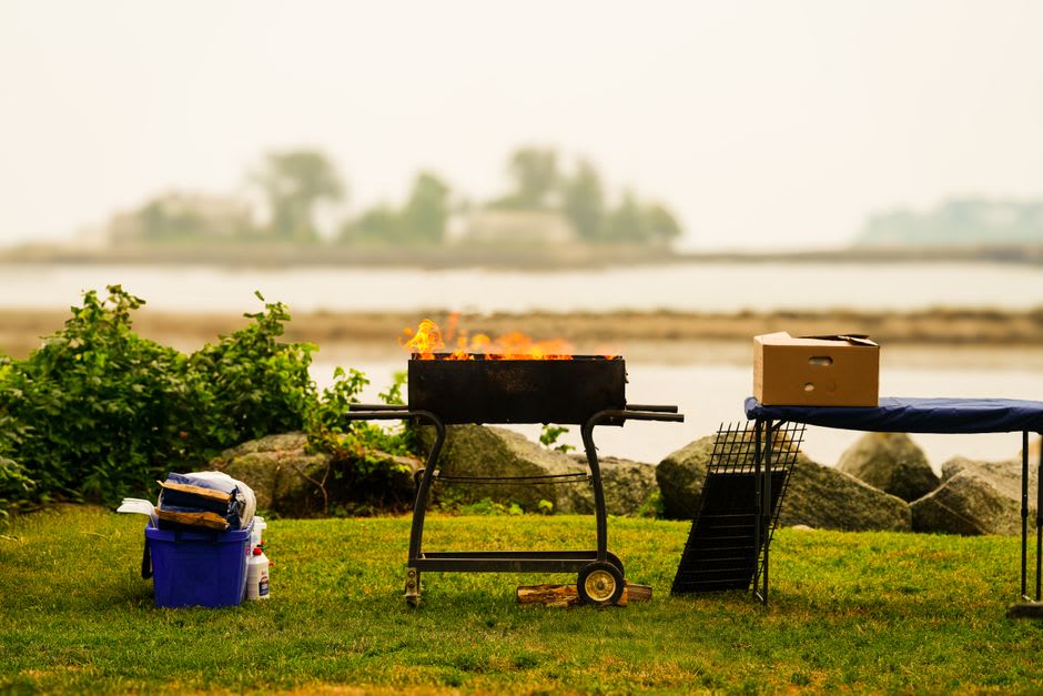 A family barbecue set up under shaded pits near the water at Al Mamzar