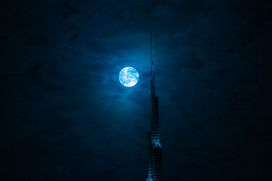 The Burj Khalifa's tapering spire against a clear blue sky, viewed from street level