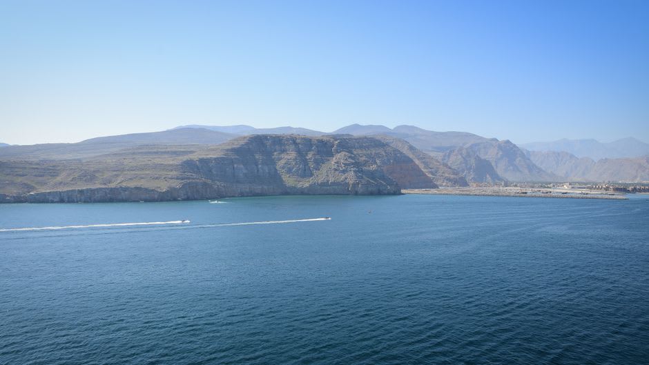 Dhow boat cruising between steep fjord cliffs near Musandam off the coast of Dibba