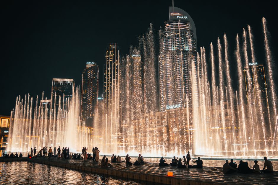 Dubai Fountain's water jets illuminated at night with Burj Khalifa rising behind