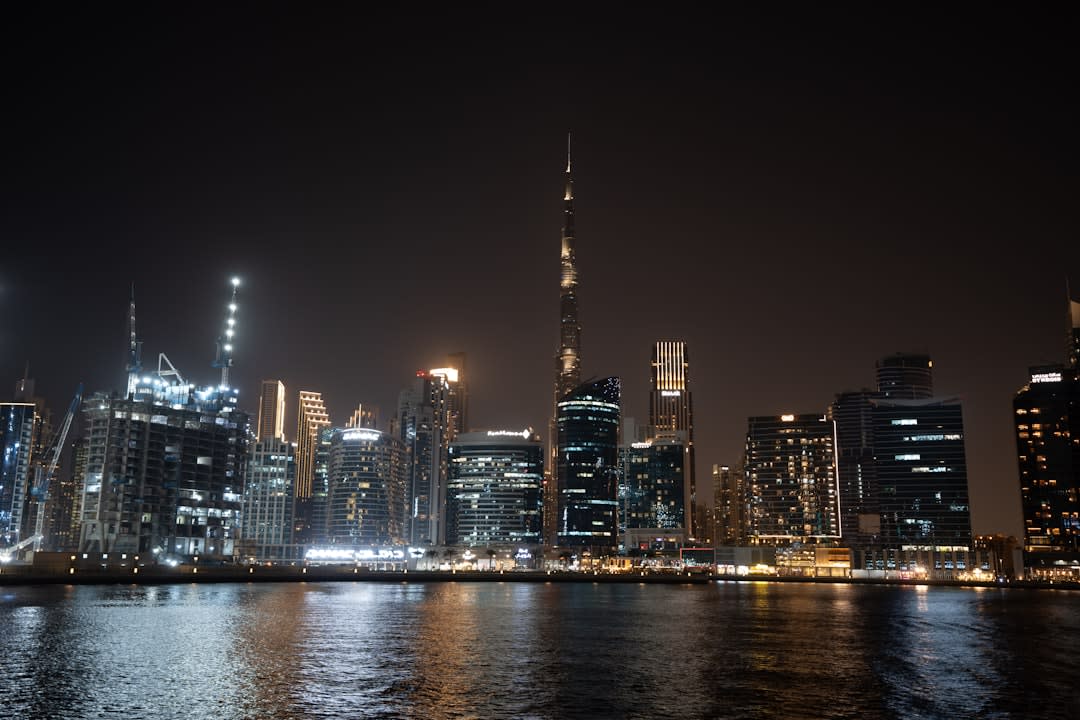 Illuminated bridge over the Dubai Water Canal reflected in still water at dusk