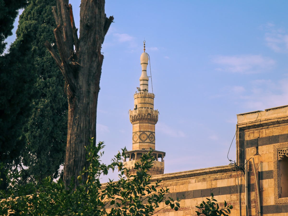 Ancient mosque with mud-brick domes against a mountainous backdrop