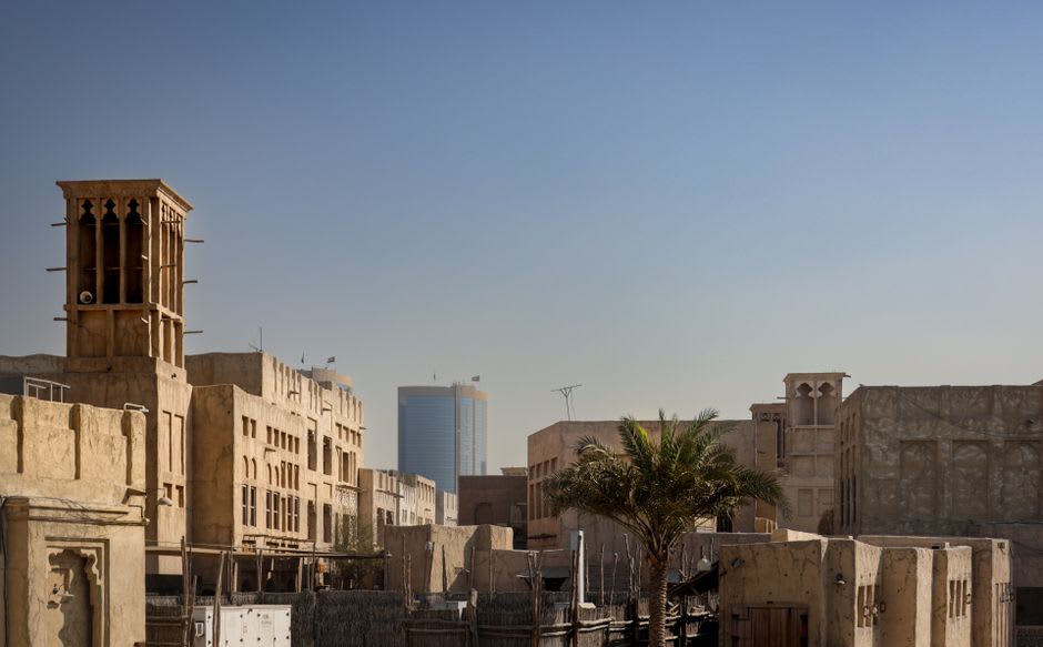 A wind tower rising above restored coral-stone buildings in the Heart of Sharjah