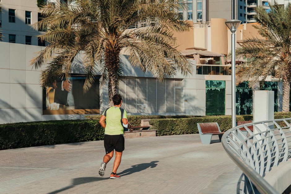 Corredores y caminantes matutinos a lo largo del paseo junto al lago en Jumeirah Lake Towers