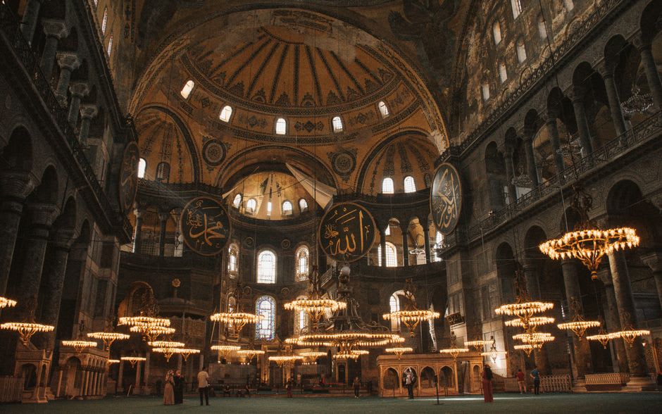 Visitors sitting inside the carpeted prayer hall of Jumeirah Mosque during a guided tour