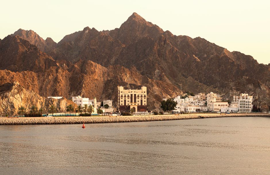 Fishing boats moored along the Khor Fakkan corniche with mountains rising behind the bay
