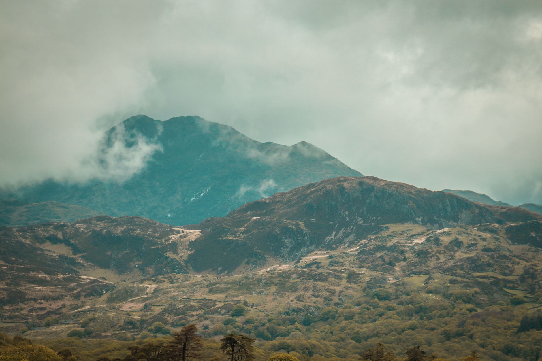 Hikers on a rocky ridge path in Snowdonia disappearing into low cloud and mist