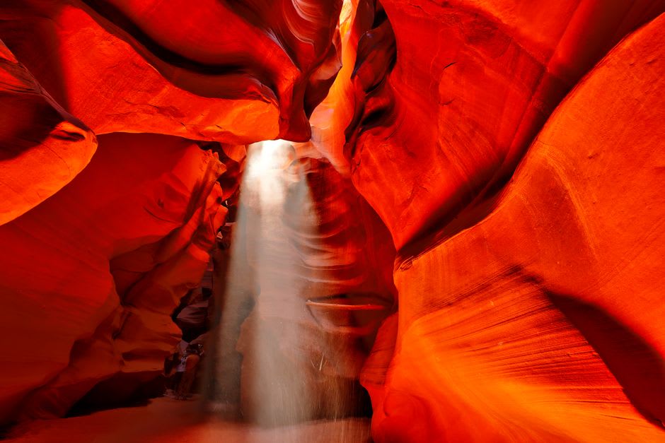 Swirling orange and purple sandstone walls curving overhead inside Antelope Canyon