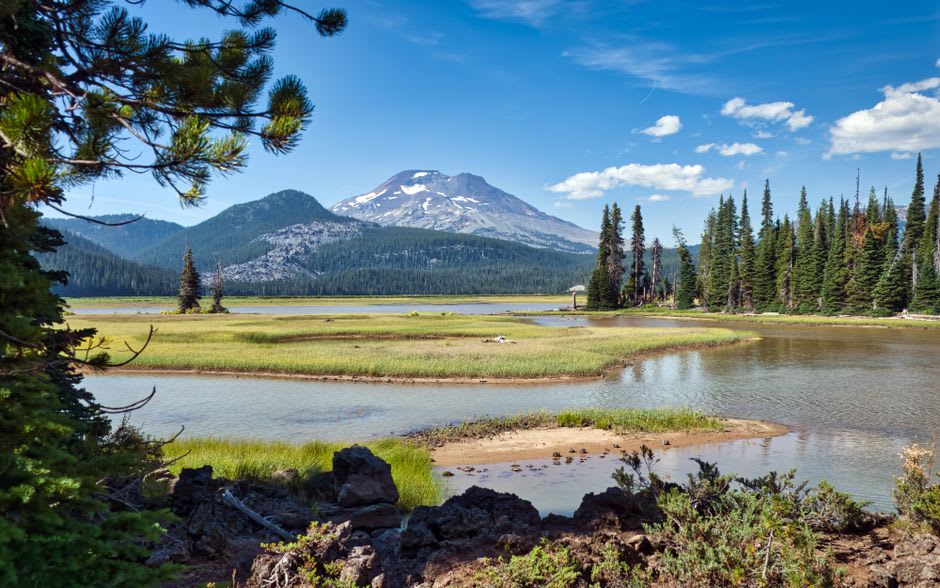 The Three Sisters volcanic peaks rising snow-capped above the pine forest, seen from a viewpoint near Bend, Oregon