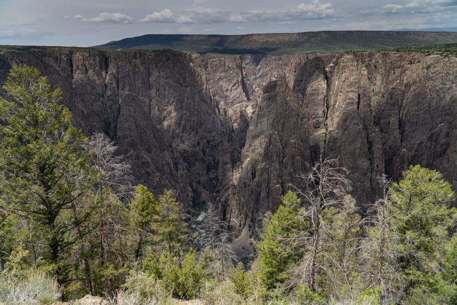 A vast dark cliff face streaked with pale bands of lighter rock