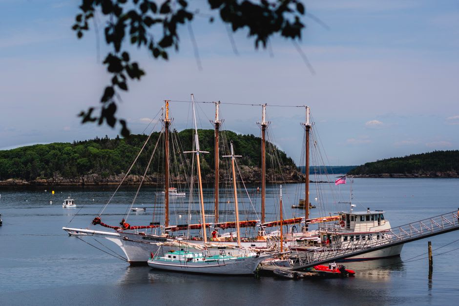 Tall-masted schooners with intricate rigging moored along the Camden waterfront
