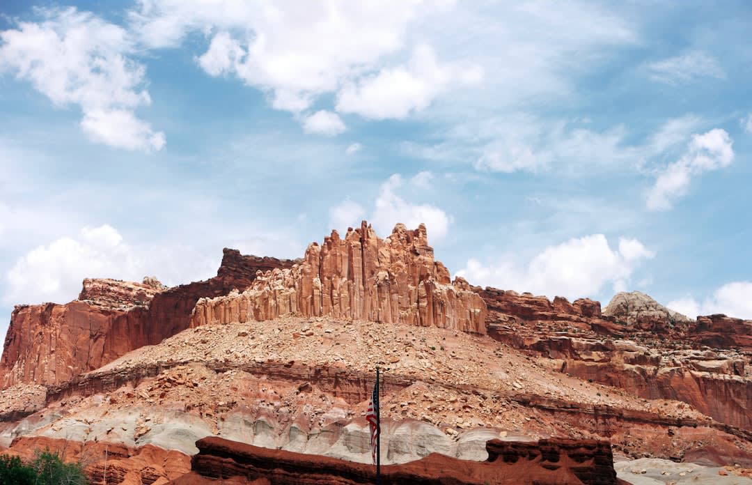 Green orchard rows below red cliffs at Fruita in Capitol Reef