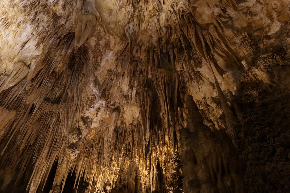 A still, glassy underground pool reflecting stalactites in the dim amber light of Carlsbad Caverns