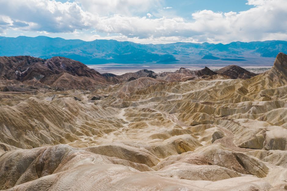 Cracked white salt polygons of Badwater Basin stretching toward hazy mountains