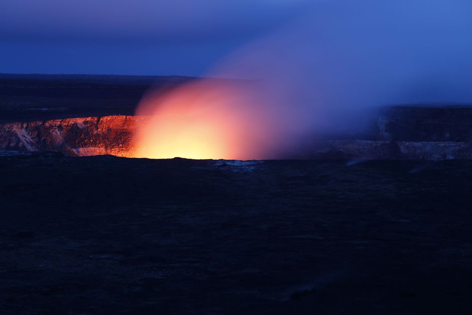 Hikers crossing the black solidified lava floor of Kilauea Iki crater
