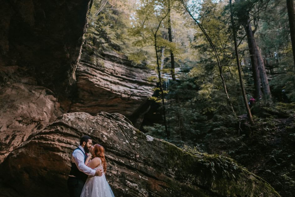A thin waterfall dropping into a vast curved sandstone amphitheater